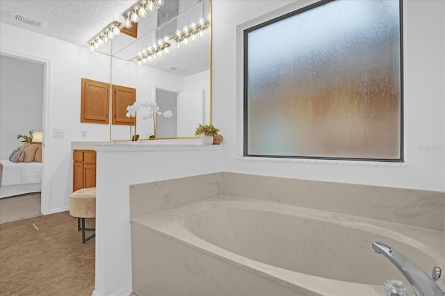 bathroom with a tub, vanity, and a textured ceiling