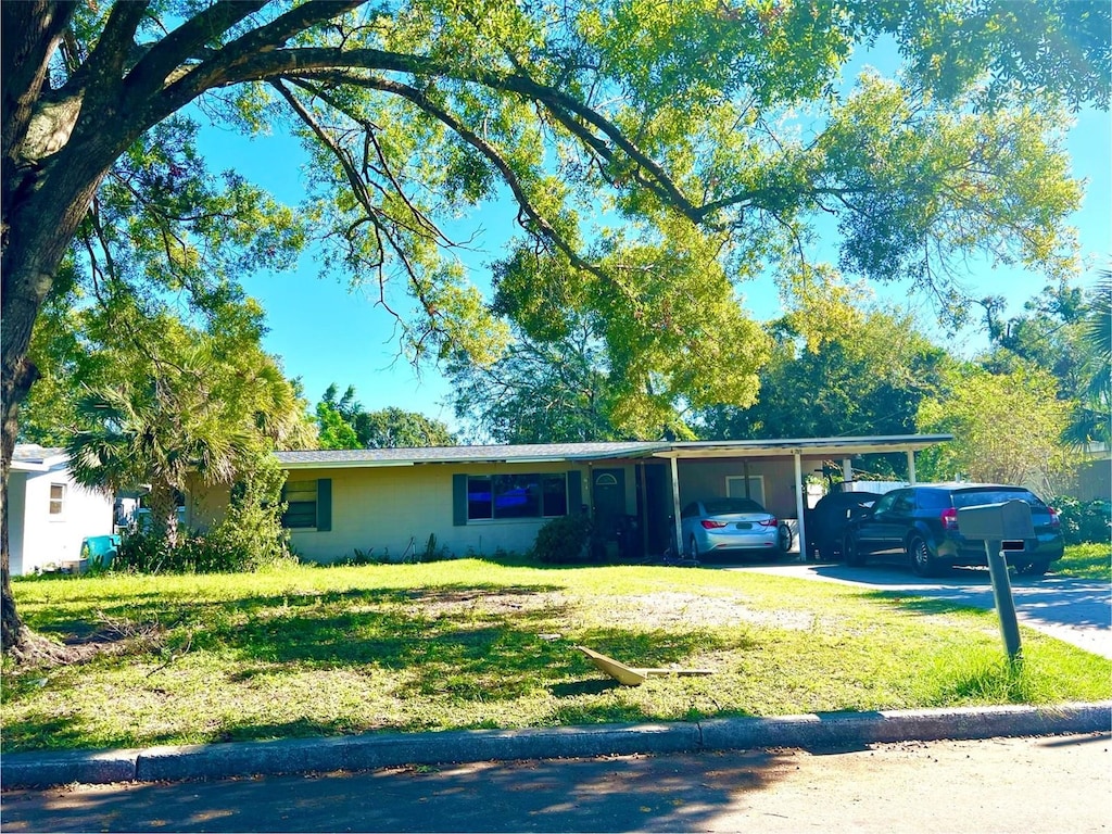 ranch-style home featuring a front lawn and a carport