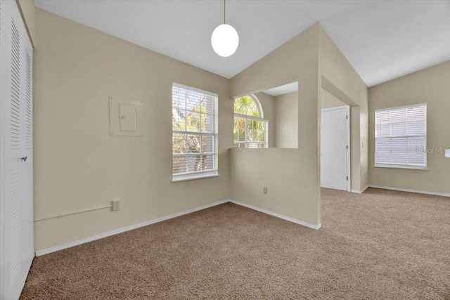 carpeted spare room featuring lofted ceiling