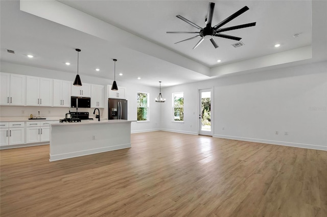 kitchen featuring white cabinetry, stainless steel fridge with ice dispenser, a kitchen island with sink, ceiling fan with notable chandelier, and light wood-type flooring