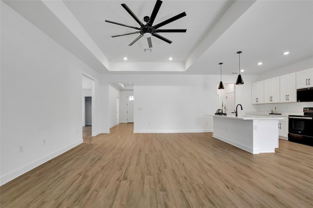 kitchen featuring a kitchen island with sink, black appliances, light hardwood / wood-style floors, white cabinetry, and hanging light fixtures