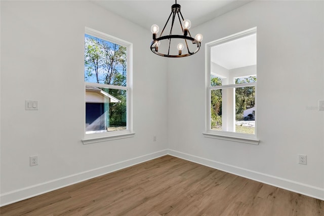 unfurnished dining area featuring a chandelier, hardwood / wood-style flooring, and plenty of natural light