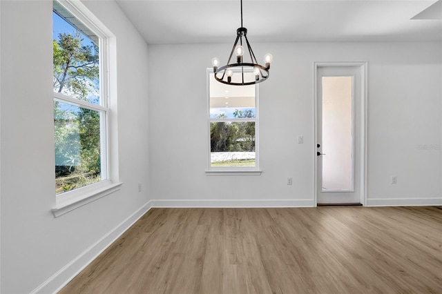 unfurnished dining area featuring a chandelier and light hardwood / wood-style floors