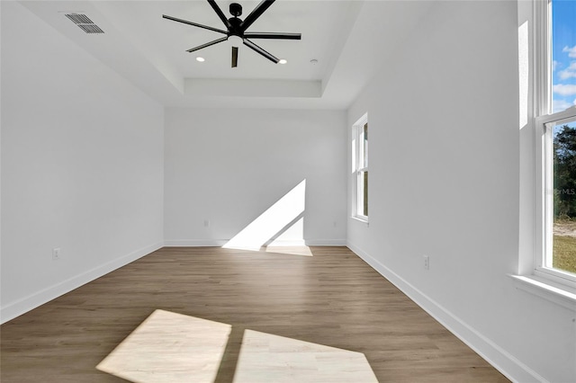 empty room featuring a tray ceiling, ceiling fan, and hardwood / wood-style flooring