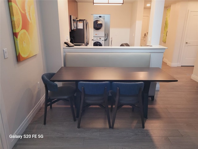 dining space featuring hardwood / wood-style floors and stacked washer / dryer