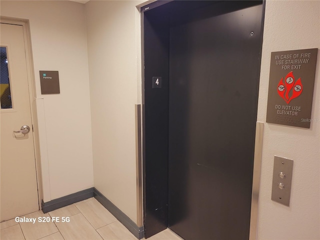 hallway with elevator and light tile patterned flooring