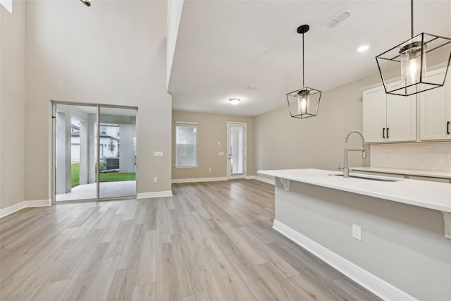 kitchen with tasteful backsplash, sink, pendant lighting, light hardwood / wood-style floors, and white cabinetry