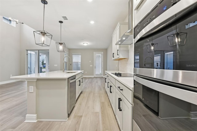 kitchen featuring a center island with sink, white cabinets, sink, light hardwood / wood-style flooring, and appliances with stainless steel finishes