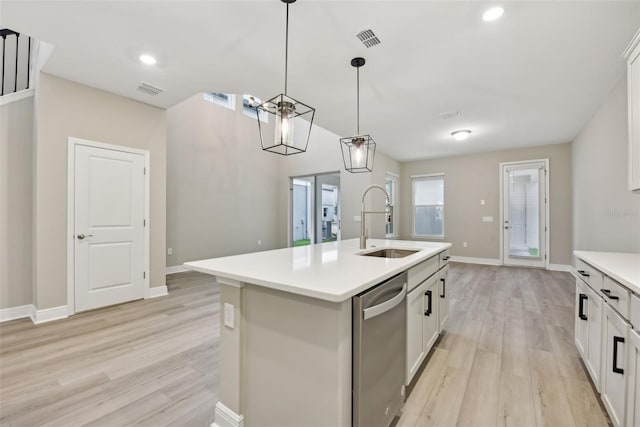 kitchen featuring a kitchen island with sink, sink, hanging light fixtures, stainless steel dishwasher, and light wood-type flooring