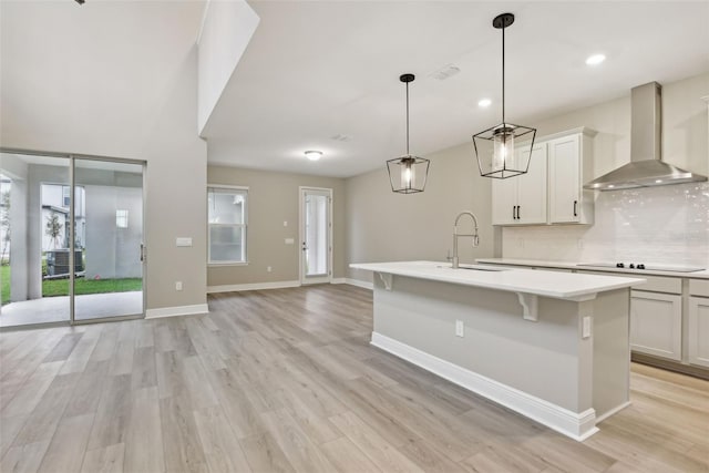 kitchen with sink, black electric cooktop, a wealth of natural light, and wall chimney range hood