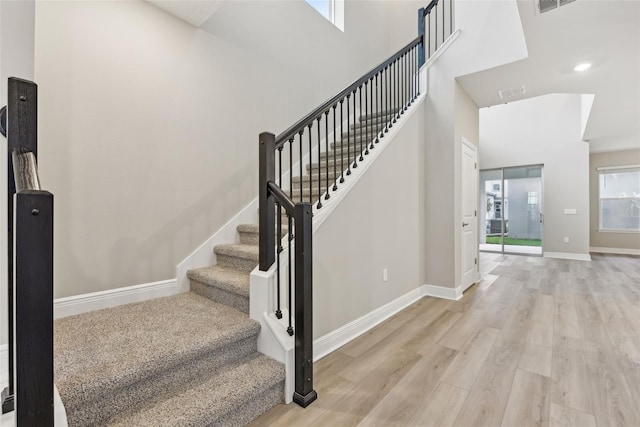 stairs with wood-type flooring and a towering ceiling