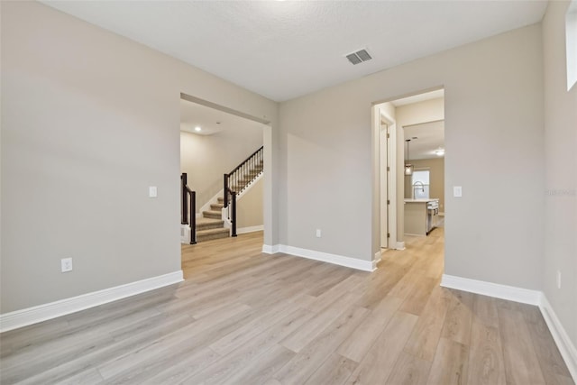 unfurnished room featuring light hardwood / wood-style flooring and a textured ceiling