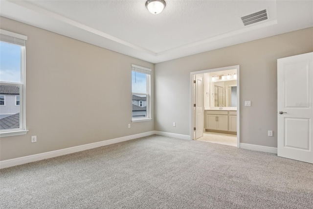 unfurnished bedroom featuring light colored carpet and ensuite bath