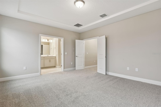 unfurnished bedroom featuring light carpet and ensuite bath