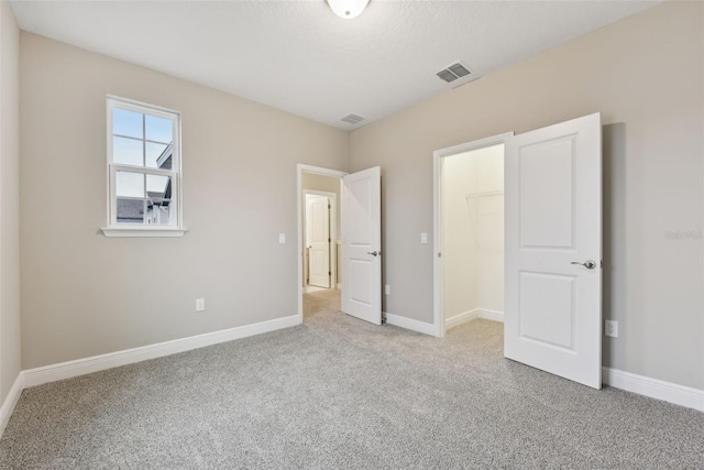 unfurnished bedroom featuring light colored carpet, a spacious closet, and a closet