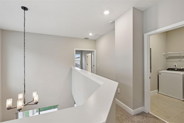 hallway featuring light carpet, a wealth of natural light, washer / clothes dryer, and a chandelier