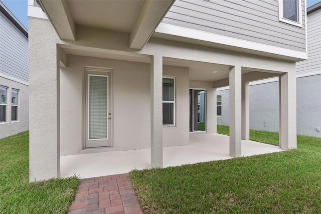 entrance to property with a lawn and a patio