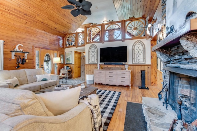 living room with ceiling fan, high vaulted ceiling, wooden walls, wood ceiling, and light wood-type flooring