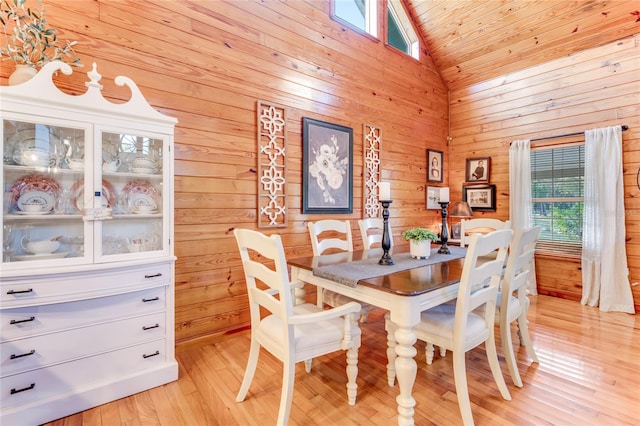 dining space with wood ceiling, wood walls, high vaulted ceiling, and light hardwood / wood-style floors