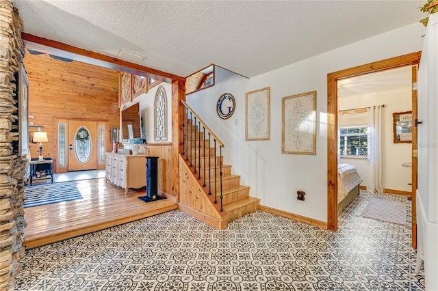 stairway featuring a textured ceiling and wooden walls