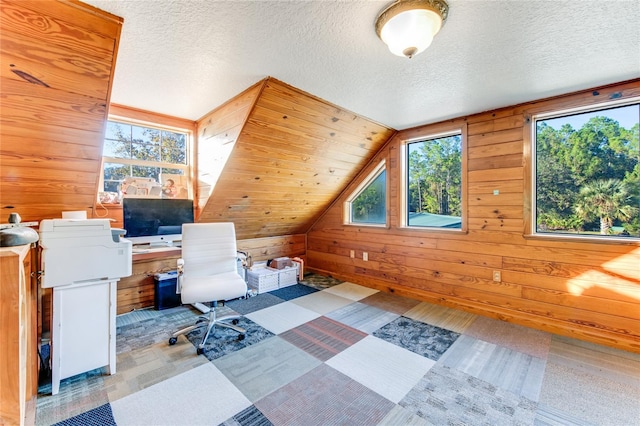 office area featuring lofted ceiling, a wealth of natural light, and wood walls