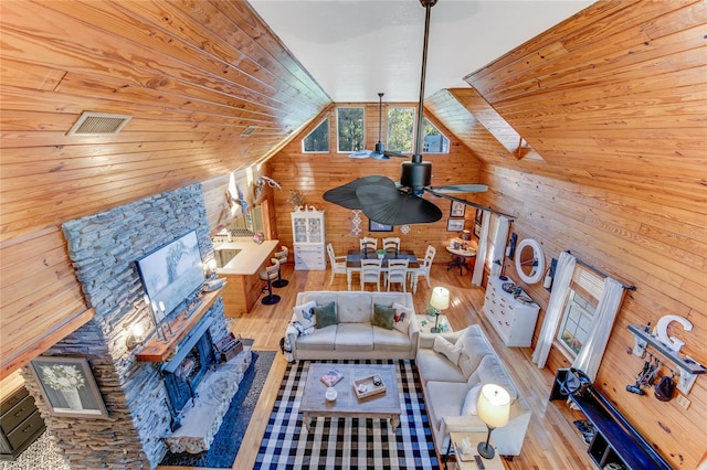 living room featuring wood walls, ceiling fan, light hardwood / wood-style floors, and lofted ceiling