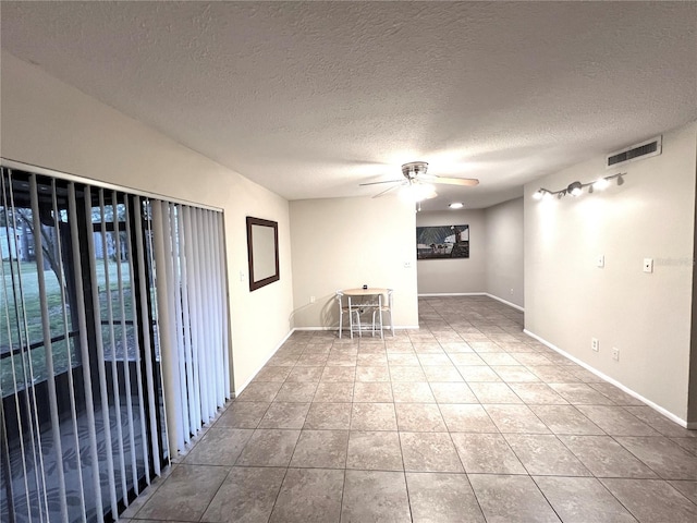 tiled spare room with ceiling fan and a textured ceiling