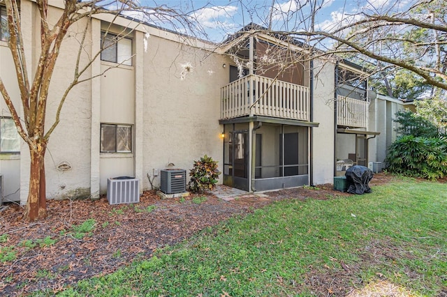 back of house with a balcony, cooling unit, a sunroom, and a lawn