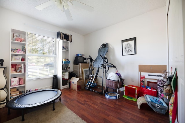 rec room with ceiling fan, dark hardwood / wood-style flooring, and a textured ceiling