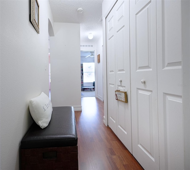 hall featuring a textured ceiling and dark hardwood / wood-style floors