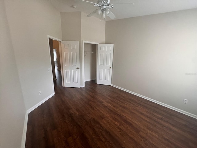 unfurnished bedroom with ceiling fan, a closet, high vaulted ceiling, and dark hardwood / wood-style floors