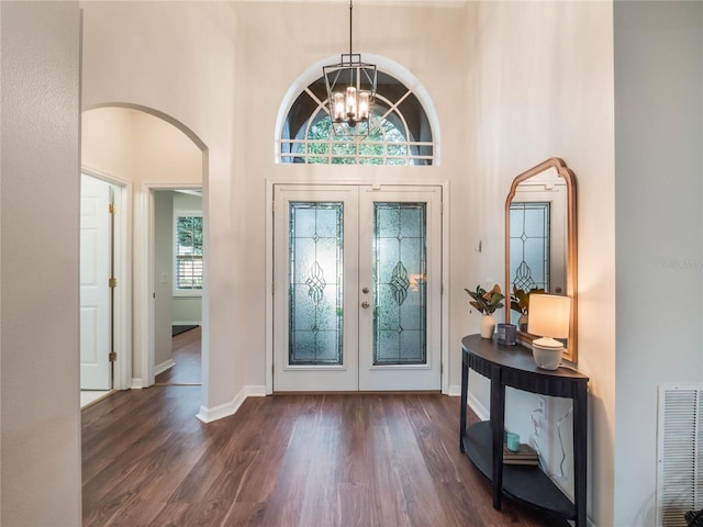 entrance foyer featuring french doors, dark wood-type flooring, a high ceiling, and a notable chandelier