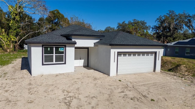 ranch-style house with a garage, a shingled roof, and stucco siding