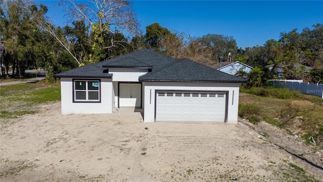 ranch-style house with a garage, a shingled roof, dirt driveway, and stucco siding