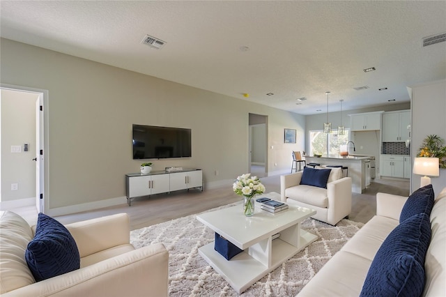 living room with baseboards, visible vents, and a textured ceiling