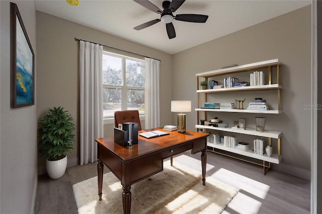 office area with light wood finished floors, baseboards, and a ceiling fan