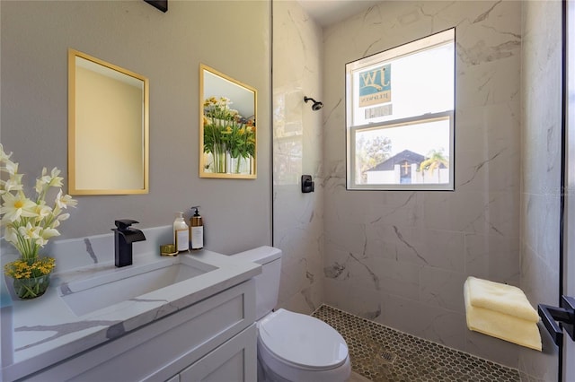 bathroom with a marble finish shower, vanity, and toilet