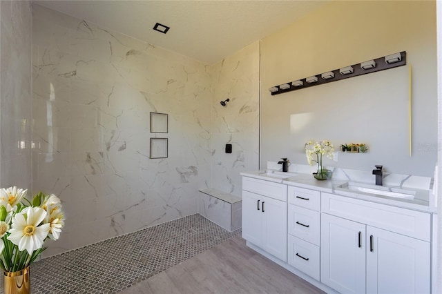 bathroom with double vanity, a marble finish shower, a sink, and wood finished floors