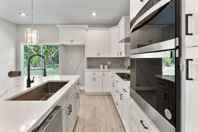 205 E 17th St, Apopka, FL 32703 - kitchen with a sink, white cabinets, hanging light fixtures, light wood-type flooring, and light stone counters