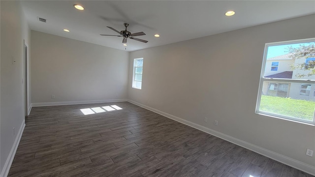 empty room with ceiling fan, a healthy amount of sunlight, and dark wood-type flooring