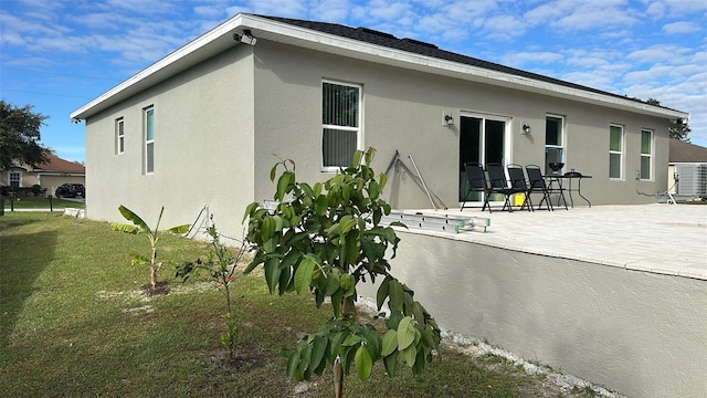 back of property featuring a lawn, cooling unit, and a patio