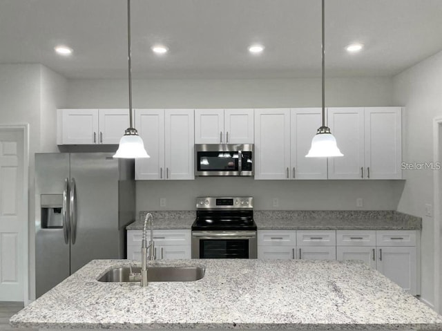 kitchen with white cabinets, decorative light fixtures, sink, and stainless steel appliances