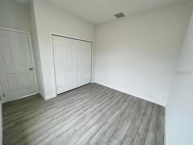 unfurnished bedroom featuring light hardwood / wood-style flooring and a closet