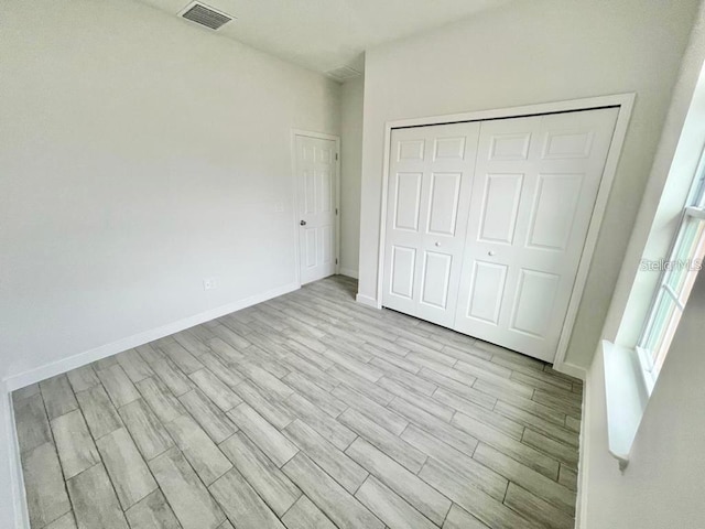 unfurnished bedroom featuring light hardwood / wood-style floors and a closet