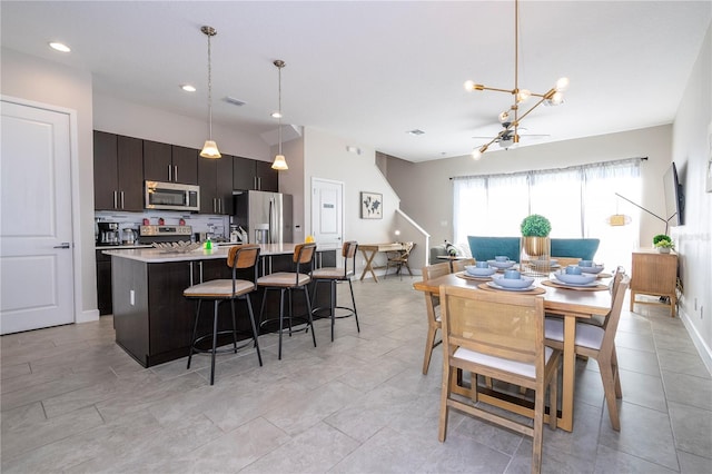 kitchen featuring pendant lighting, stainless steel appliances, a kitchen island with sink, and a breakfast bar area