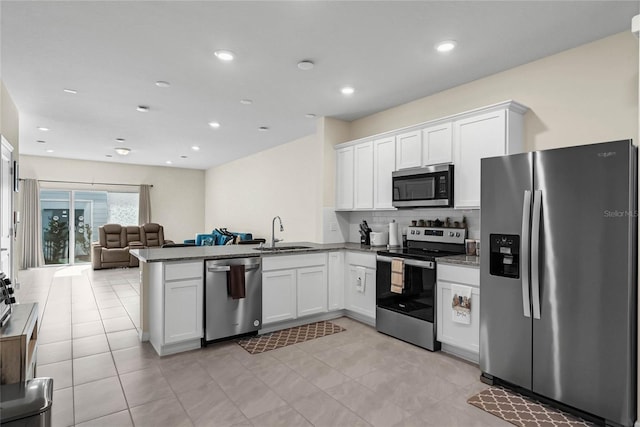 kitchen featuring white cabinetry, sink, backsplash, kitchen peninsula, and appliances with stainless steel finishes