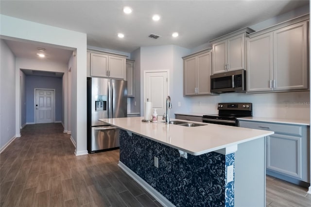 kitchen with dark hardwood / wood-style floors, sink, stainless steel appliances, and a kitchen island with sink