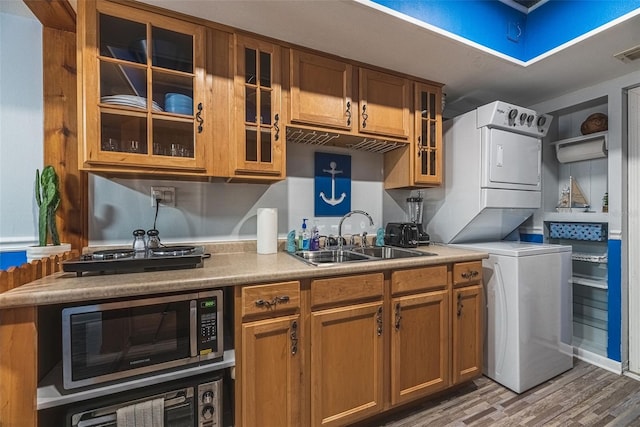 kitchen featuring sink, dark wood-type flooring, and stacked washer and clothes dryer