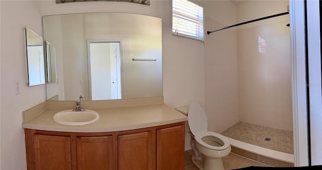 bathroom featuring tiled shower, tile patterned flooring, vanity, and toilet