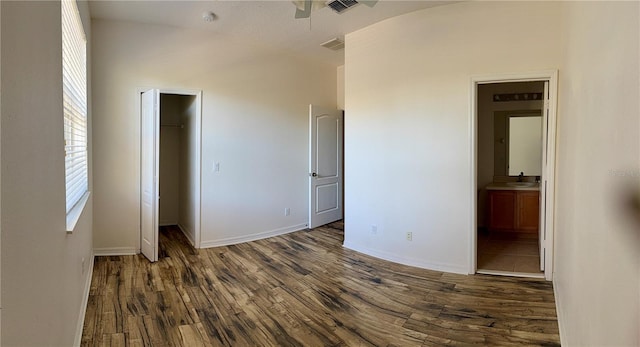 unfurnished bedroom with a walk in closet, dark hardwood / wood-style flooring, sink, connected bathroom, and a closet